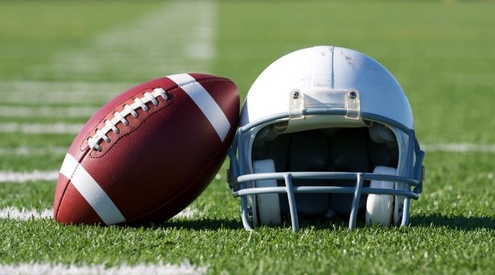 A football and helmet laid beside each other on a football field