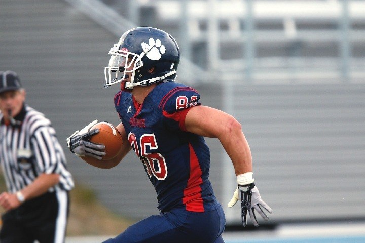 football receiver running with ball during game