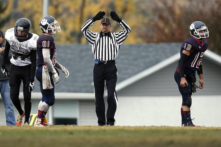 referee calls penalty before throwing his flag during a football game